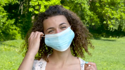 Woman Removing Surgical Face Mask Smiling Outside