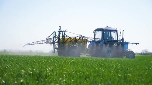 Farming Tractor Spraying on Field with Sprayer, Herbicides and Pesticides at Sunset. Farm Machinery