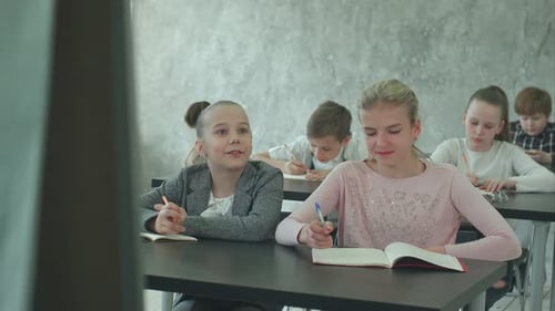 Children Writing in Classroom During Class Lesson