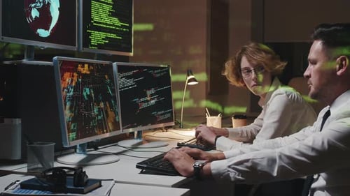 Two Professionals Working with Code at Night