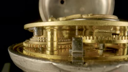 Inside View of a Moving Clockwork of Golden Mechanical Clock on Black Isolated Studio Background