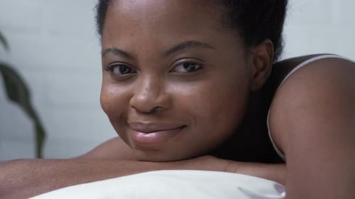 Relaxed Woman Smiling on a Pillow in Bed