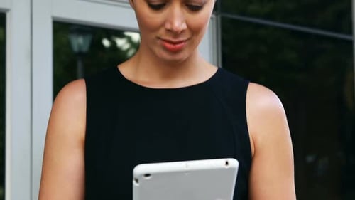 Businesswoman using digital tablet outside office building
