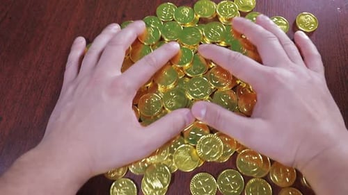 Hands Arrange Pile of Gold Coins on Surface