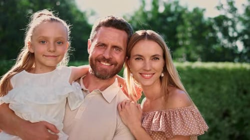 Family Looking at Camera. Mother and Daughter Hugging Father on Backyard