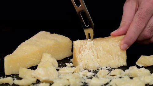 Morceaux de parmesan à pâte dure avec couteau sur planche à découper