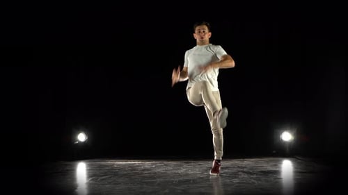 Junger Mann tanzt Breakdance im schwarzen Studio