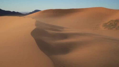 Slow motion strong wind blowing sand and dust overtop of large sand dunes in the summer heat isolate