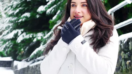 Woman in White Coat Warms Hands in Winter