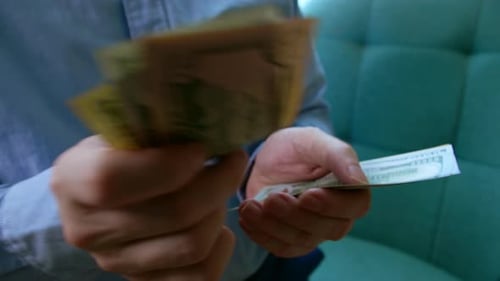 Person Counting US Dollars in Bright Light