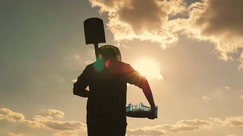 Silhouette of Farmer Carrying Shovel at Sunset