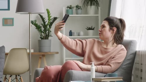 Woman Discussing Medical Mask and Sanitizer via Video Call on Smartphone