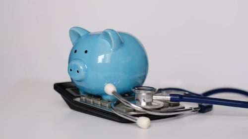Piggy Bank with Stethoscope and Calculator on White Background Health Insurance Concept