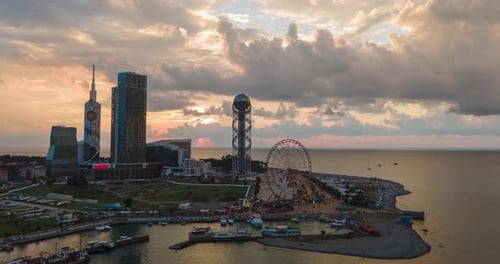 Aerial hyperlapse of Ferris wheel, alphabetic tower, skyscrapers and embankment of Batumi city