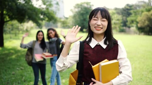 Three Female Women Students Waving Hands in the Park While Focus is on Asian Woman in the Front