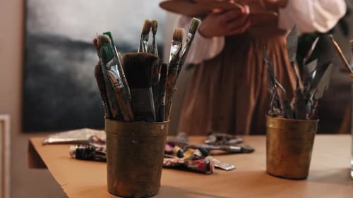 Art Studio Young Woman Artist Changing Brushes From the Jar on the Table