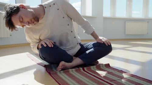 Man Stretches Indoors on Yoga Mat During Daytime