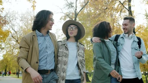 Happy Young Couples Walking Outdoors in Park on Sunny Autumn Day Talking