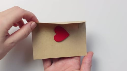 Hands Open Small Brown Envelope With Red Heart