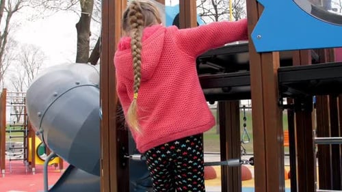 Junior Schoolgirl Climbs Up Small Playground Ladder