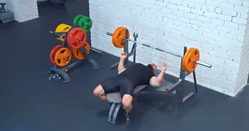 Brutal Man Powerlifter legt sich auf eine Sportbank, nimmt die Langhantel. Powerlifter schüttelt die Brustmuskulatur