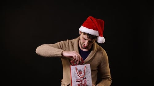 Man in Santa Hat Pulls Gift from Bag