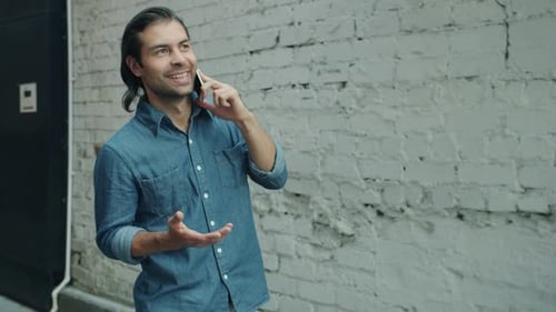 Cheerful Middle Eastern Man Talking on Mobile Phone Walking and Gesturing Outdoors in City