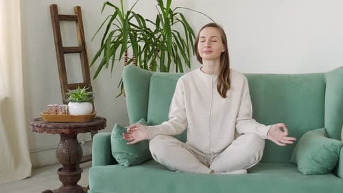 Woman Meditating on Sofa in Relaxing Pose