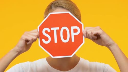 Femme fermant le visage avec un panneau d'arrêt, protestation contre le commerce sexuel et l'esclavage
