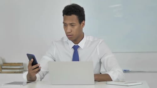 Young Adult Speaks on Cell Phone at Desk