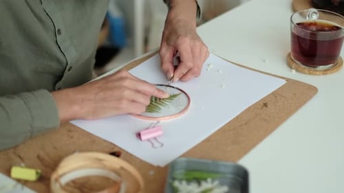 Adult Arranging Pressed Flowers in Embroidery Hoop