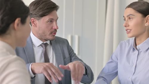 Serious Male and Female Business People Talking in Office