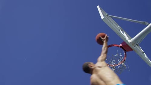 Foto em câmera lenta de baixo ângulo de homem fazendo um layup de basquete