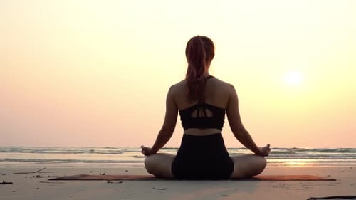Slow motion of woman practice yoga lotus pose to meditation with summer vacation on the beach