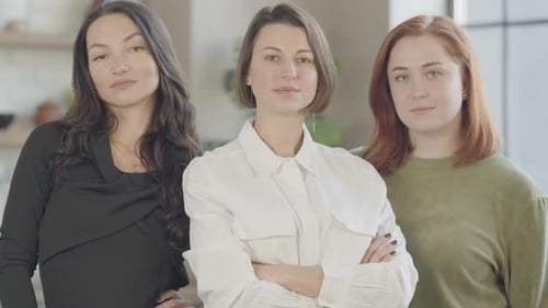 Three Confident Gorgeous Young Women Posing Indoors Looking at Camera