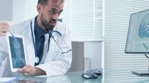 Professional Doctor Holding a PC Tablet in Hands and Explaining Something on a X Ray Scan