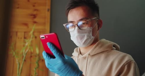 Adult Using Smartphone Wearing Mask and Gloves