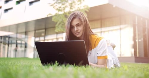 Frau mit Laptop arbeitet im Freien bei Sonnenuntergang