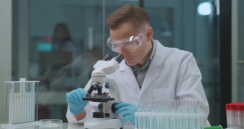 Professional Technician of Medical Laboratory Is Working with Microscope Apparatus, Researching
