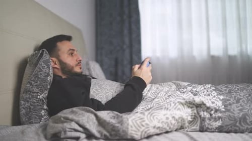 Man Playing Video Games in Bed