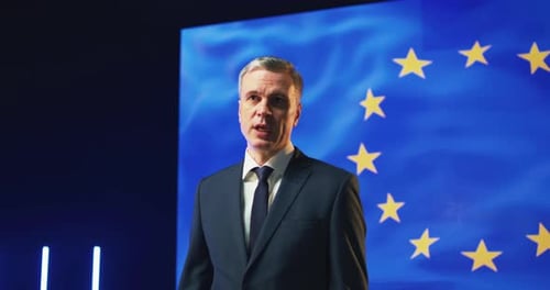 Suited Man Giving Political Speech With Flag Backdrop