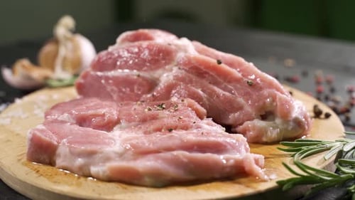 Close Up Side View of Raw Slices of Fresh Steak Meat with Falling Salt on It.