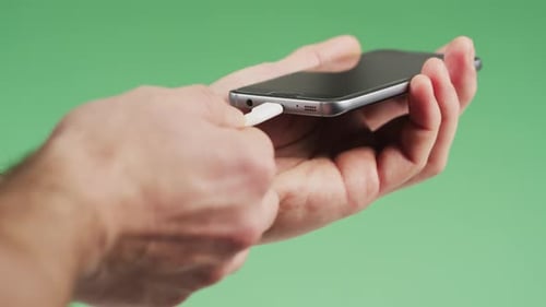 Hand Connecting White Cord to Smartphone
