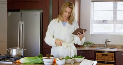 Woman in Robe Uses Tablet in Kitchen