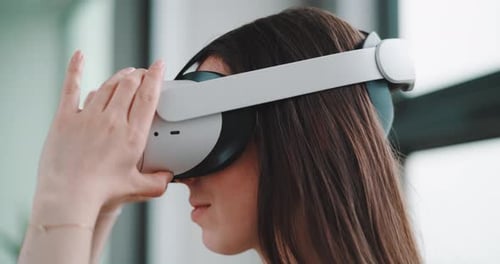Close up of young woman from left side putting on vr goggles