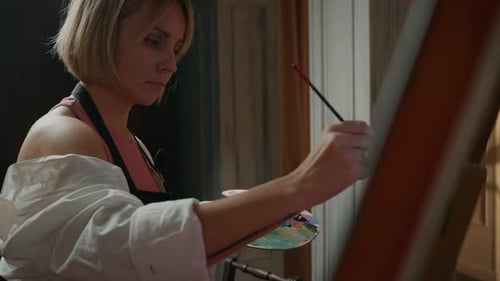 Close Up Portrait of Young Concentrated Woman Artist in Apron Painting Picture at Studio Using