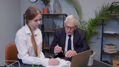 Woman and Senior Man Working in Office