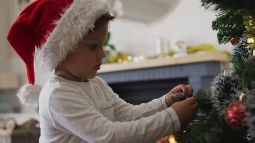 Boy Decorates Christmas Tree with Ornaments at Home