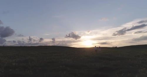 Couple Walking in a Field During Sunset