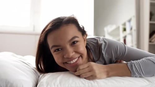 Smiling Woman Lying on Bed in Bright Bedroom